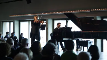 A women playing a violin beside a male pianist.
